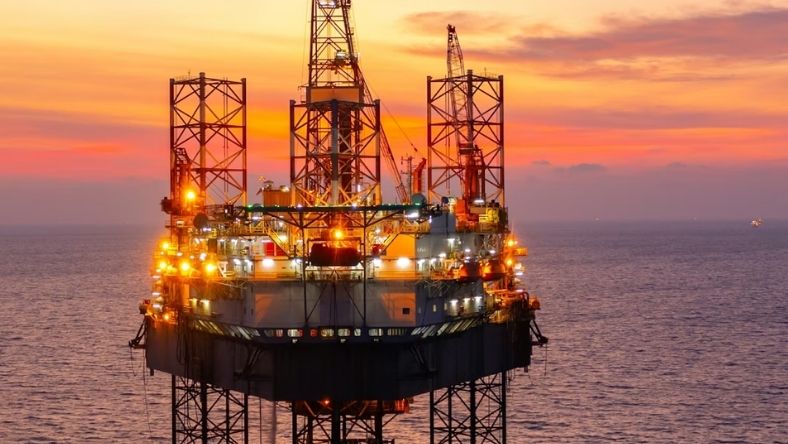 Offshore oil platform illuminated at sunset over open sea