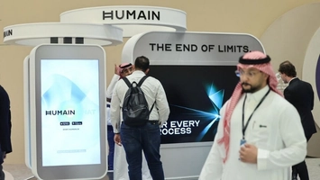 A HUMAIN branded exhibition booth with large digital screens and visitors at an indoor technology conference